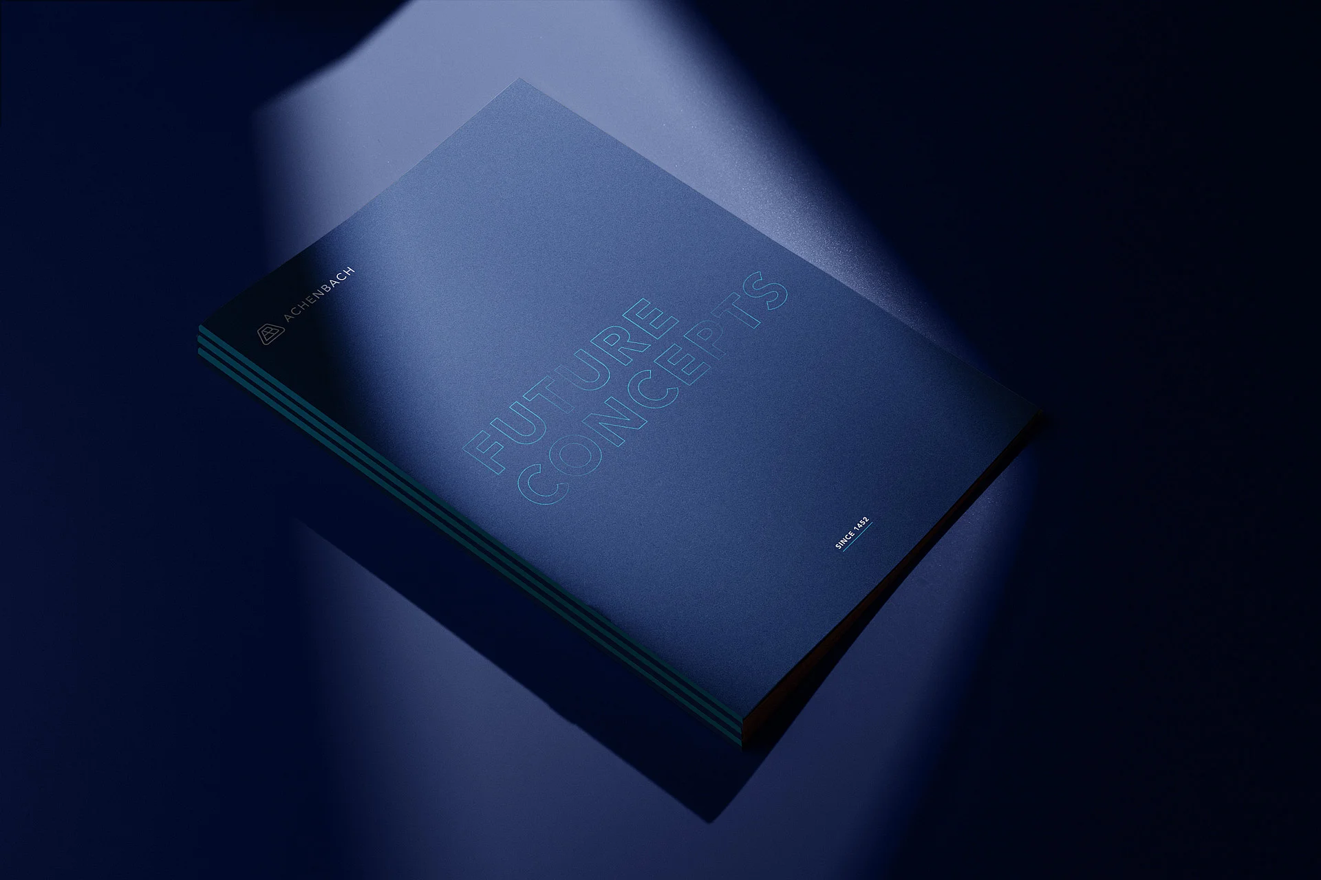 Blauer Ordner mit "FUTURE CONCEPTS" Schrift und "ACHENBACH" Logo Ein blauer Ordner mit der Schrift "FUTURE CONCEPTS" und dem Logo "ACHENBACH". Beleuchtet von einer Lichtquelle.