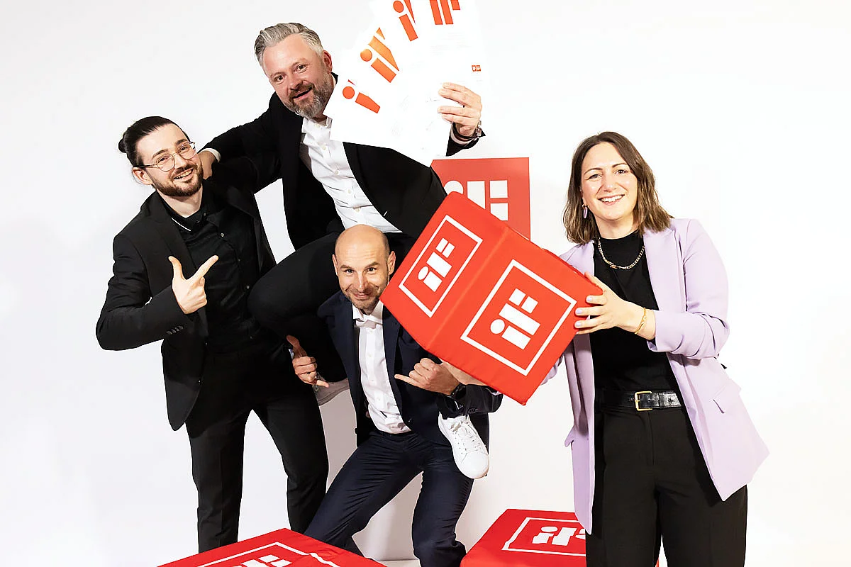 Gruppenfoto mit roten Kissen und Urkunden Vier Personen posieren mit roten Kissen und Urkunden, vor einem weißen Hintergrund.